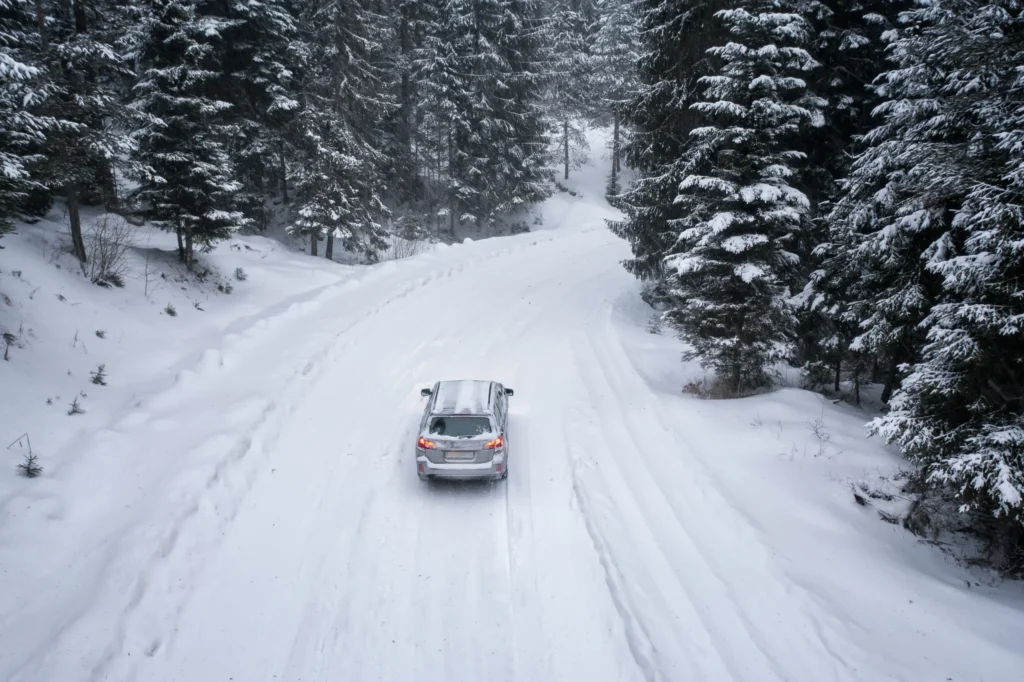 Bil åker längs snötäckt väg